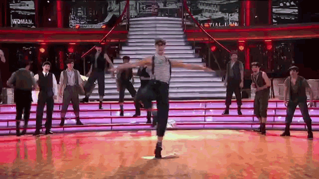 a group of men are dancing on a stage with a sign that says woman on it