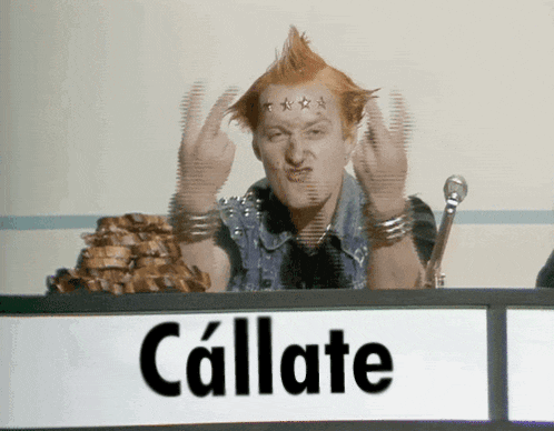 a man with a mohawk is giving the middle finger in front of a sign that says callate