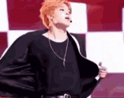 a man wearing a black shirt and a black jacket is holding a microphone and dancing on a stage .