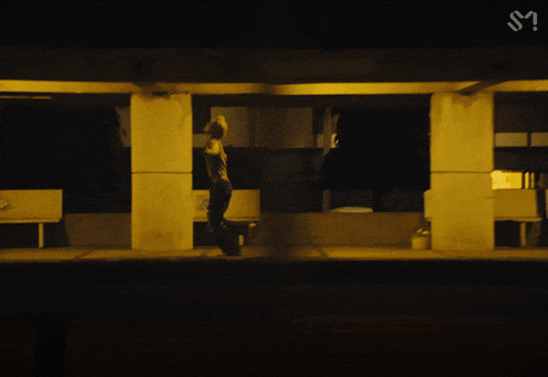 a silhouette of a person walking in front of a sign that says m