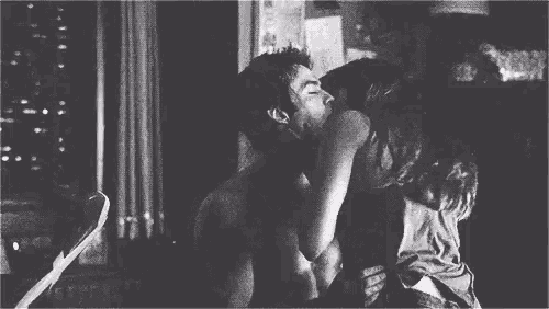 a black and white photo of a man and woman hugging each other in a room .