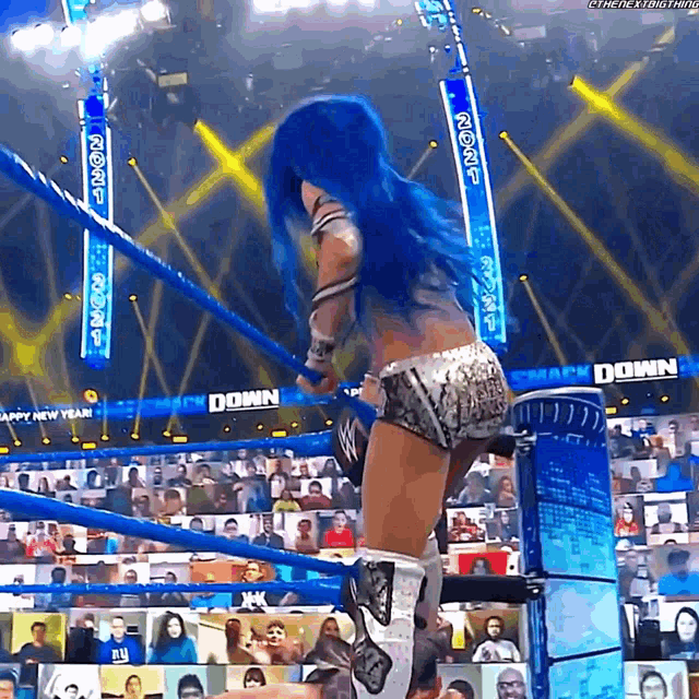 a woman with blue hair is in a wrestling ring with a banner that says smack down on it