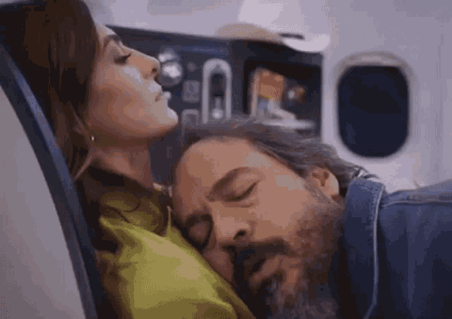 a man and woman are sleeping on an airplane .