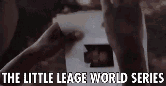 a close up of a person holding a piece of paper with the words `` the little leage world series '' on it .
