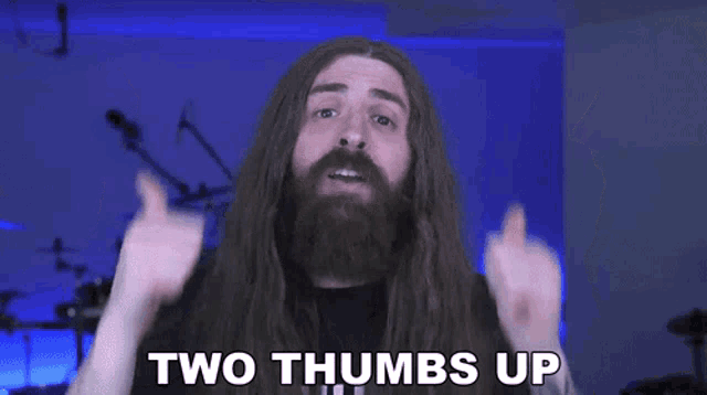 a man with long hair is giving two thumbs up