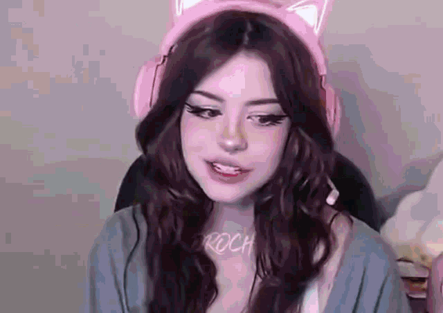 a girl wearing a pair of pink cat ears headphones is sitting in a chair .