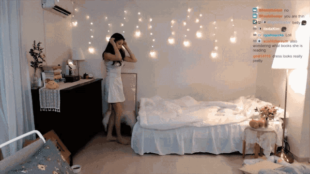 a woman in a white dress is standing in front of a bed in a bedroom