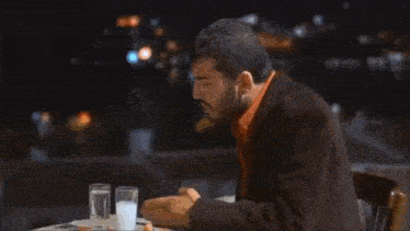 two men are sitting at a table with a pitcher of water on it .