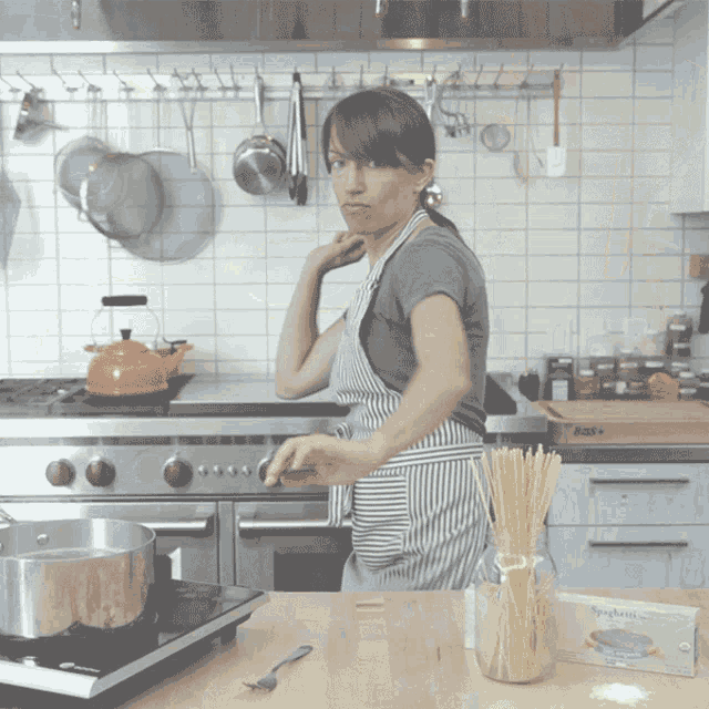 a woman in a kitchen with a box of spaghetti on the table