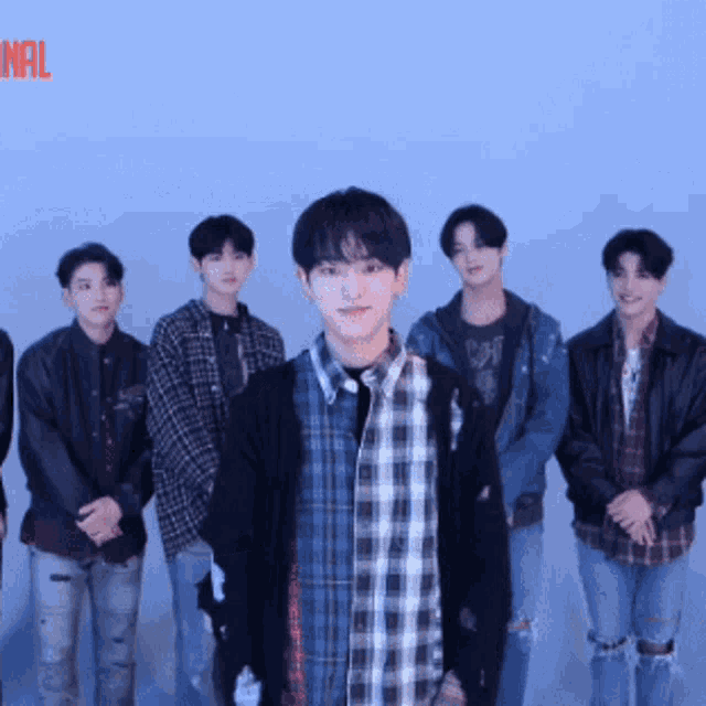 a group of young men are standing in front of a blue wall with the word nal in the corner