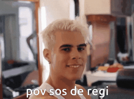 a man with blonde hair and a white tank top is smiling with the words pov sos de regi written below him .