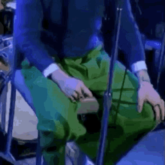 a man in a blue suit and green pants is sitting on a chair .