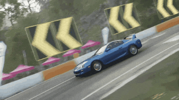 a blue car is driving down a road with arrows pointing to the right