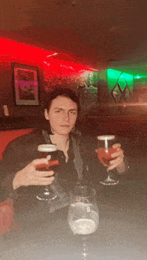 a man is sitting at a table with two glasses of beer and a glass with the letter s on it