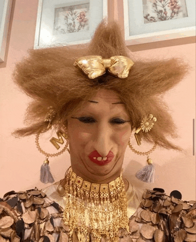 a woman wearing a wig with the letter m on her earrings