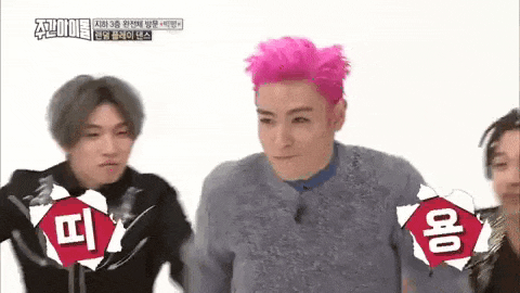a group of young men are standing next to each other . one of the men is wearing pink hair .