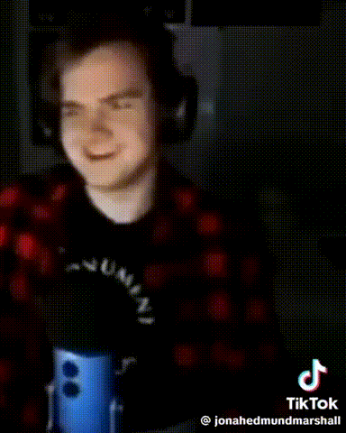 a young man wearing headphones and a plaid shirt is standing in front of a blue microphone .