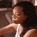 a woman wearing glasses and a white tank top is sitting in front of a laptop computer .