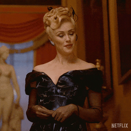a woman in a black dress is standing in front of a statue and a sign that says netflix on it