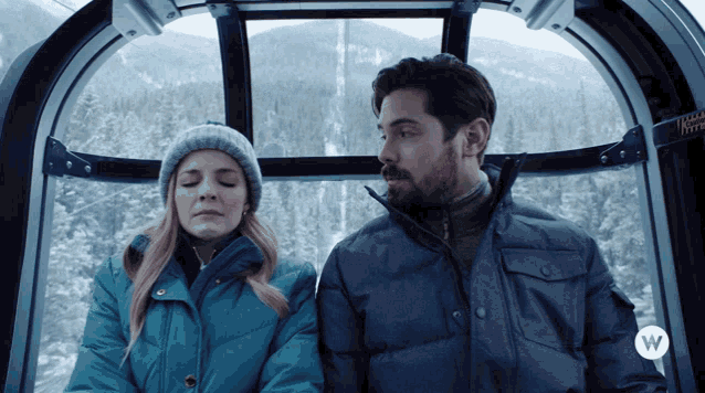 a man and a woman are sitting in a gondola with the letter w on the bottom left