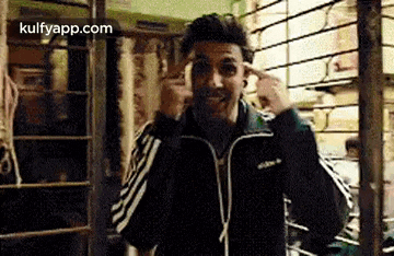 a man in a black jacket is making a funny face and pointing at his head .