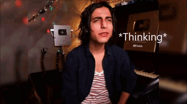 a young man is sitting in front of a piano with the words * thinking * written above him