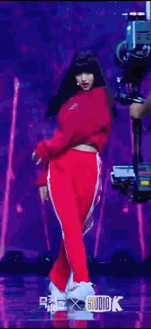a woman in a red sweater and red pants is standing on a stage .