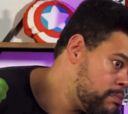 a close up of a man 's face with a beard and a captain america shield in the background .
