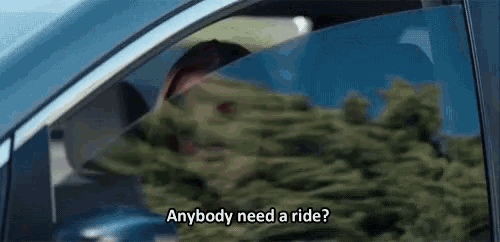 a man is sitting in a car looking out the window and saying `` anybody need a ride ? ''
