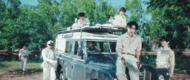 a group of people are standing around a car with a roof rack