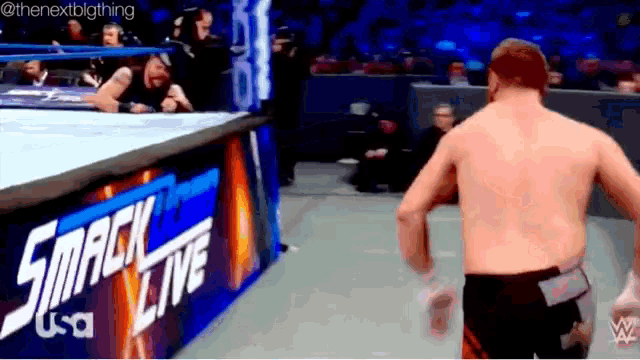 a shirtless wrestler is standing in front of a sign that says smack live