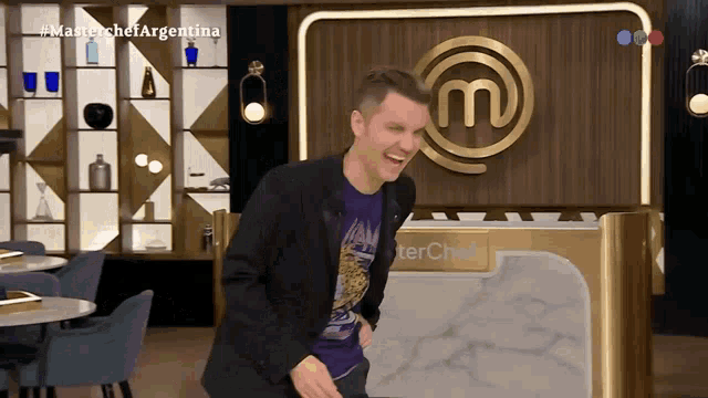 a man is laughing in front of a master chef sign