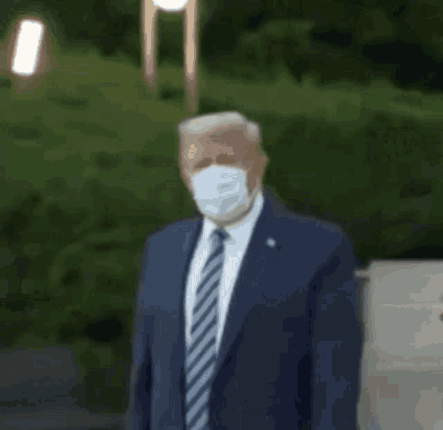 a man in a suit and tie is wearing a mask and giving a thumbs up