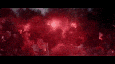 a person is standing in a dark room with a red light coming out of it .