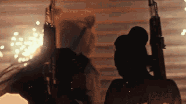 a silhouette of a man holding a gun with fireworks in the background