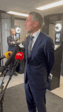 a man in a suit and tie stands in front of a microphone that says cnn