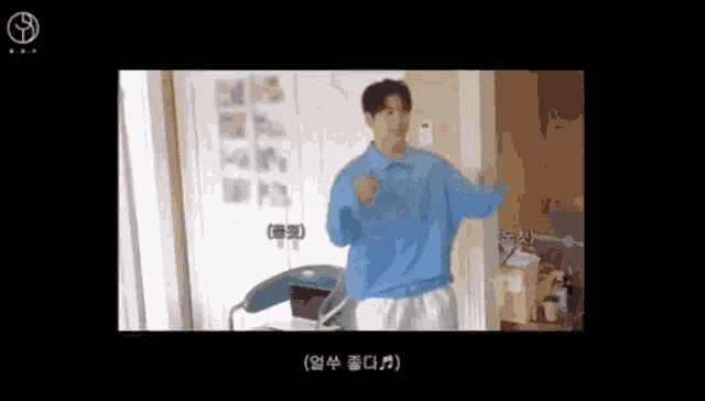 a man in a blue sweater is dancing in a room with a chair .