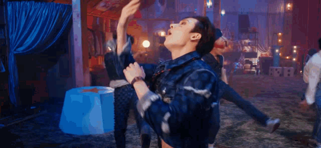 a group of people are dancing in a room with a blue curtain .