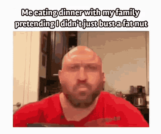 a bald man in a red shirt is eating dinner with his family and pretending he did n't just bust a fat nut .