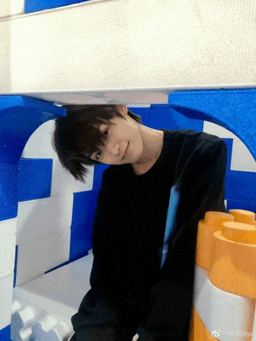 a young man in a black shirt is standing in a room with blue and white walls
