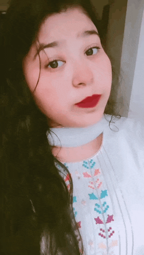 a girl with long black hair and red lipstick is taking a selfie .