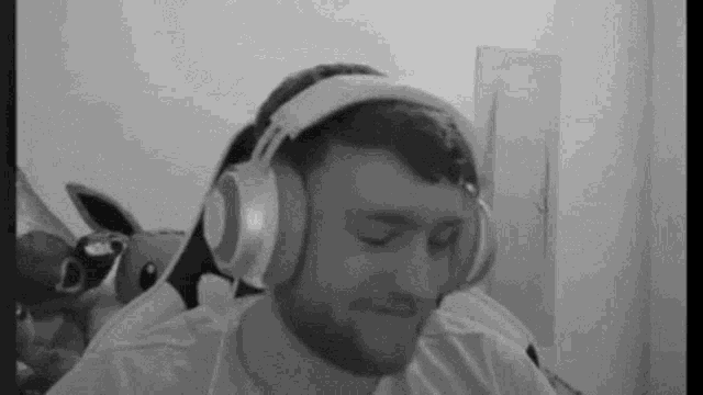 a black and white photo of a man wearing headphones and making a funny face .