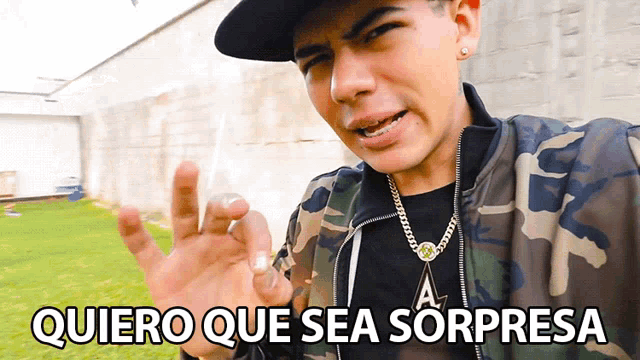 a man in a camo jacket giving an okay sign with the words quiero que sea sorpresa below him