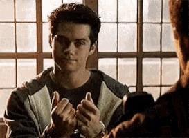 a man in handcuffs is giving a thumbs up sign .