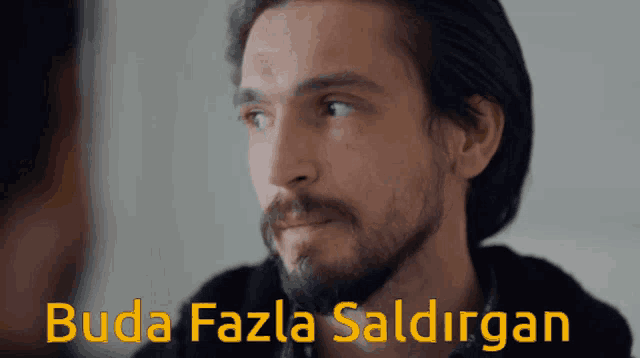 a man with a beard looks at another man with the words " buda fazla saldiran " below him