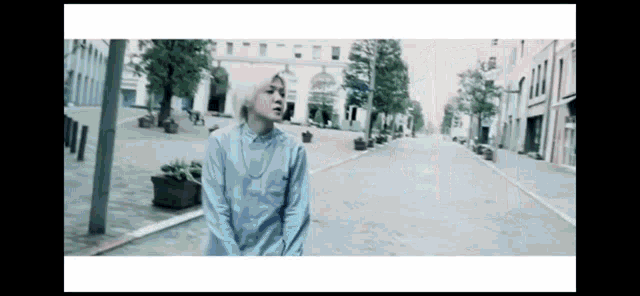 a man in a blue shirt is standing in the middle of a street