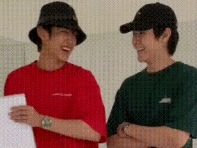 two men wearing hats and t-shirts are standing next to each other .