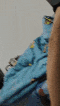 a blurred image of a person standing next to a stack of blue clothes