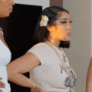 a woman with a flower in her hair is standing next to another woman .