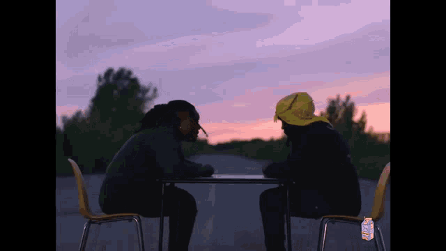 two men are sitting at a table with a carton of lemonade in the foreground .